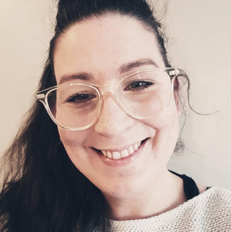 Bildet er av Kristine Ask. Hun er forsker på dataspill. Hun har mørkt hår og briller med lys innfatning. Hun smiler.