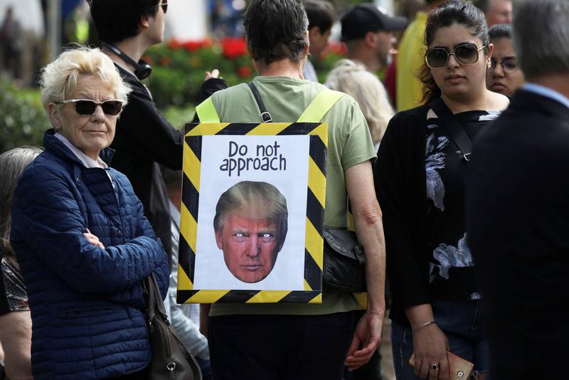 Bildet viser folk med en plakat der Trumps øyne er hvitet ut. «Ikke kom nær», står det på plakaten.