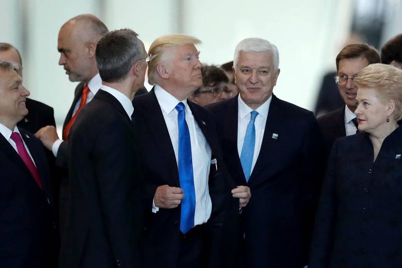 Bildet viser Donald Trump som retter på jakken sin etter å ha kommet seg fremst i bildet. Han står blant en gruppe statsledere.