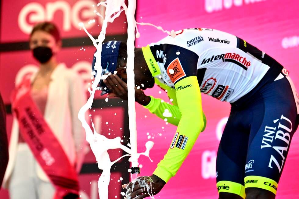 Biniam Girmay fikk en champagnekork i øyet da han feiret sin historiske etappeseier i Giro d'Italia tirsdag. Foto: Massimo Paolone / LaPresse / AP / NTB