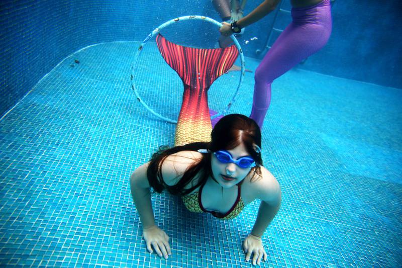 Bildet viser en kvinne som svømmer med havfruehale under vann.