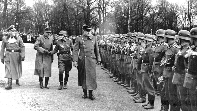 Bildet viser politikeren Vidkun Quisling som går langs en rekke med soldater under andre verdenskrig.