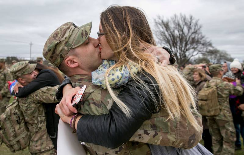 Bildet viser en kaptein i militært antrekk som kysser kona i USA.