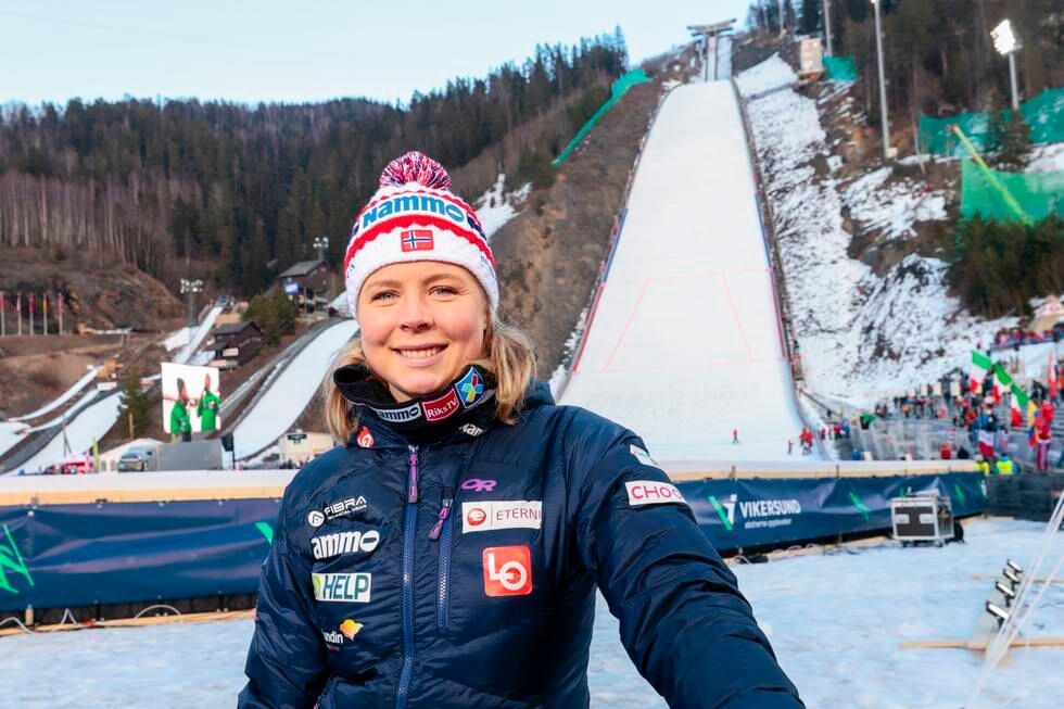 Bildet er av Maren Lundby som står foran skiflygingsbkkeni Vikersund. Bildet er tatt på vinterstid. Hun har på vinterklær og lue, og det er snø bakken. Foto: Geir Olsen / NTB