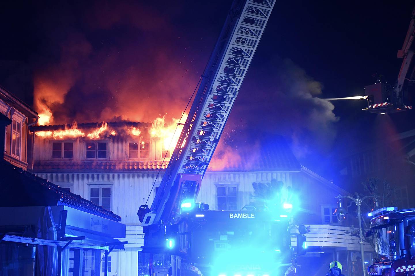 Det brenner i et bygg i Kragerø med leiligheter og en butikk. Politiet melder at brannen har spredd seg til nabobygg. Foto: Theo Aasland Valen / NTB