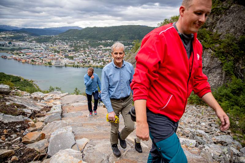 Bildet viser Jonas Gahr Støre som går oppover et fjell sammen med andre. Det er utsikt mot Mosjøen i bakgrunnen. 