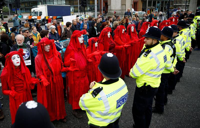 Bildet viser en rekke politifolk som står mot en rekke av folk  i røde kapper.