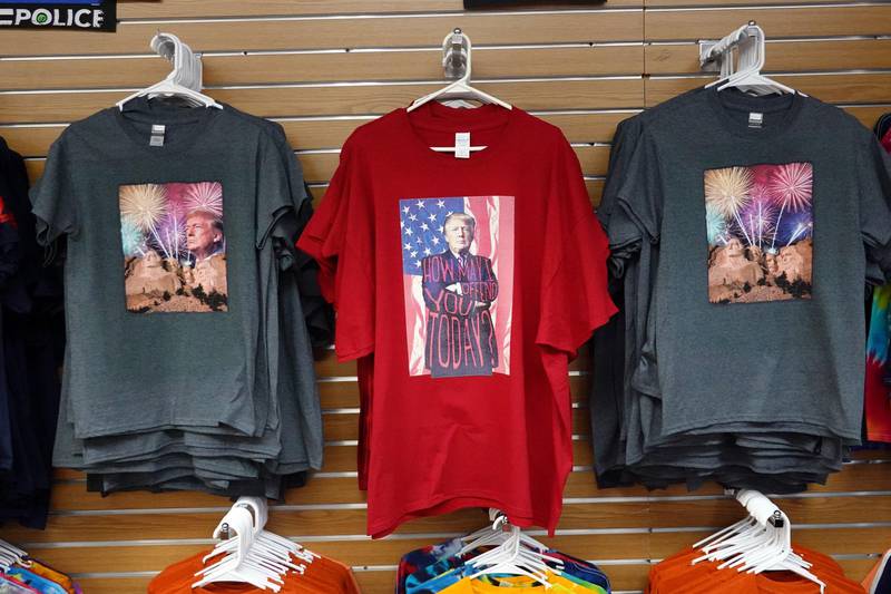 Bildet viser tre T-skjorter med to ulike motiv. De er til salgs for tilhengere av Donald Trump, som er motiv på begge. Det ene har han armene i kryss og teksten "Hvordan kan jeg fornærme deg i dag?". Den andre er av Trumps hode som en del av Mount Rushmore-monumentet.