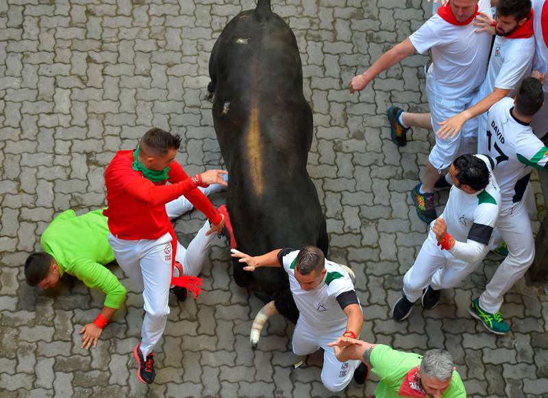 Bildet viser en okse som stanger mennesker i gatene i Pamplona.