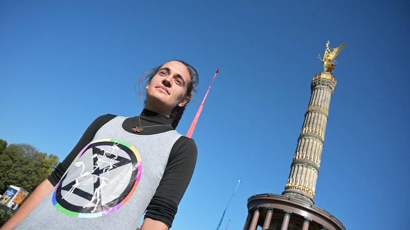 Bildet viser Carola Rackete. Hun har på vest med XR sin logo. Hun står foran Seierssøylen.