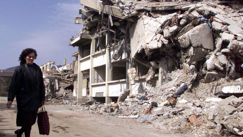 Bildet viser ruiner etter Natos bombing i Jugoslavia. En ukjent dame går forbi.