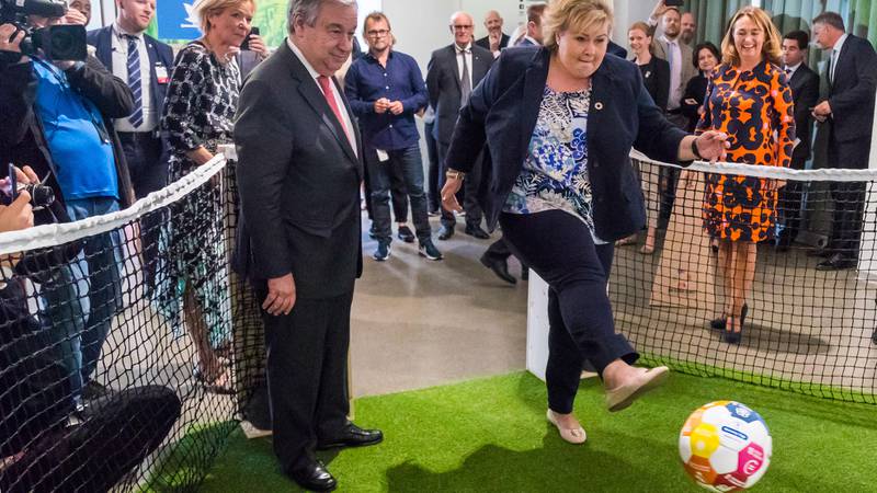 Bildet viser Erna Solberg som sparker en fotball. António Guterres ser på.