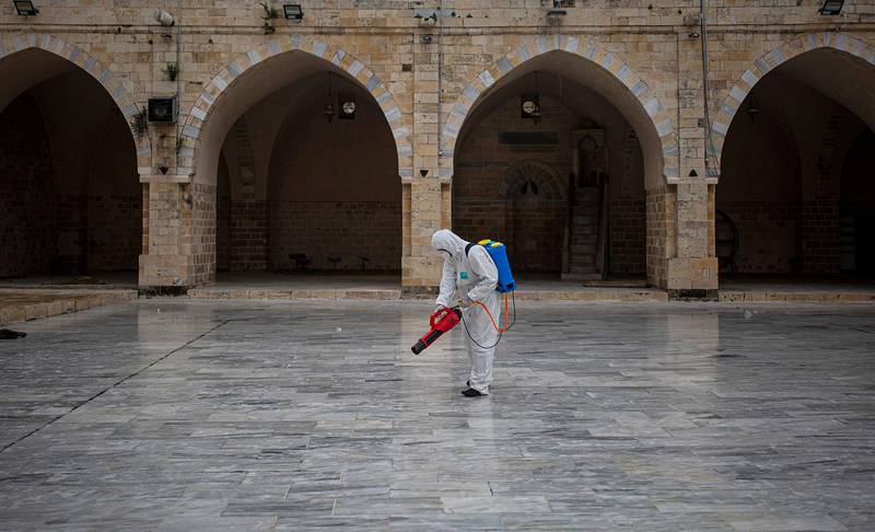Palestinian Health workers spray disinfectant as a precaution against the coronavirus in the Al-omari Mosque in Gaza City, Thursday, March 12, 2020. For most people, the new coronavirus causes only mild or moderate symptoms. For some it can cause more severe illness. (AP Photo/Khalil Hamra)