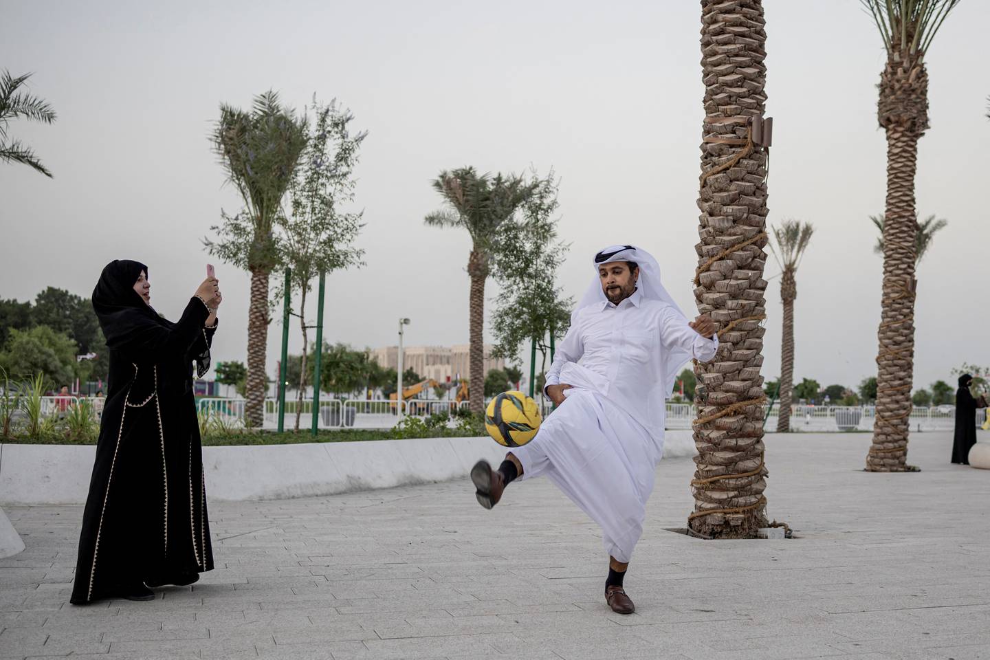 Bildet viser en mann i Qatar som spiller fotball i gata.