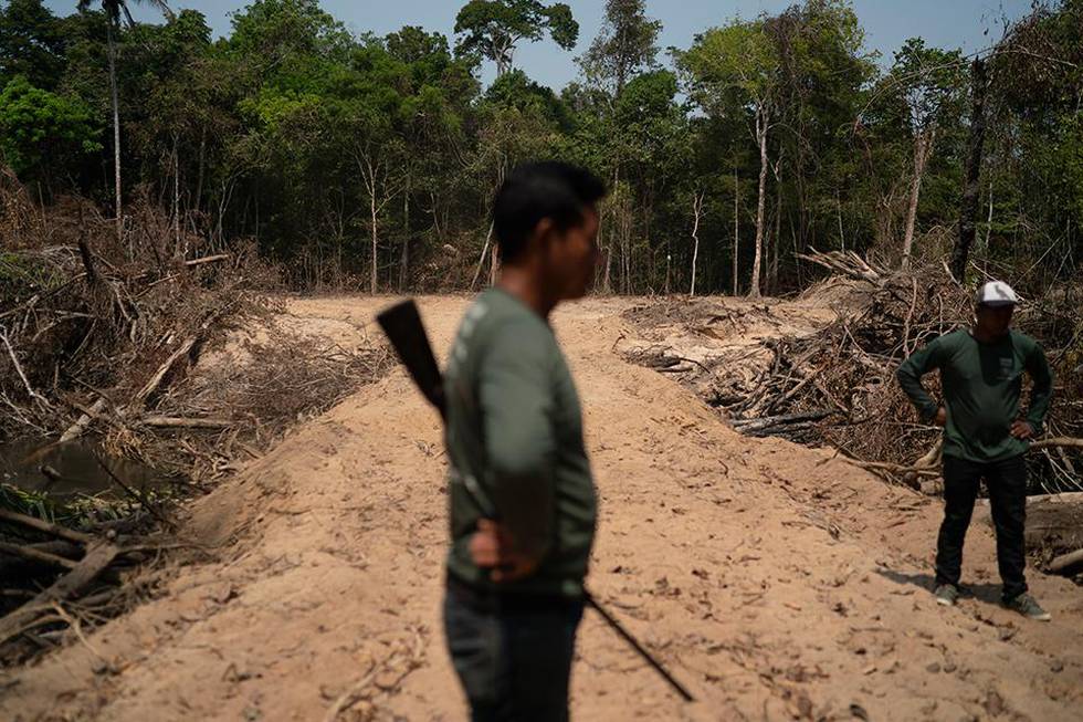 Bildet viser en mann med våpen. Han står på en vei der kriminelle hogget ned skogen. Det er i Altamira i Brasil. Urfolket i området passer på skogen.