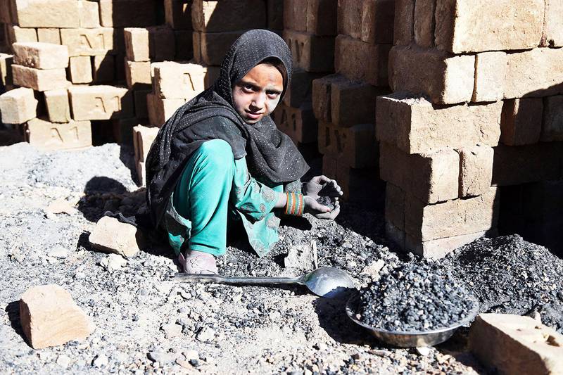 Bildet viser en jente som sitter på huk og arbeider med stein.