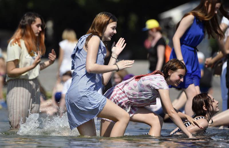 Bildet viser jenter som bader med klærne på i en fontene i