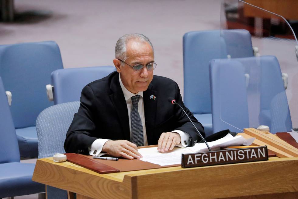 Bildet er av Ghulam Isaczai. Han sitter bak en trepult med et skilt som sier Afgahnistan. Det er tomme blå seter bak ham. Isaczai har vært representant for Afghanistan i FN. Han er en eldre mann i dress, med briller, kort hår og uten skjegg.