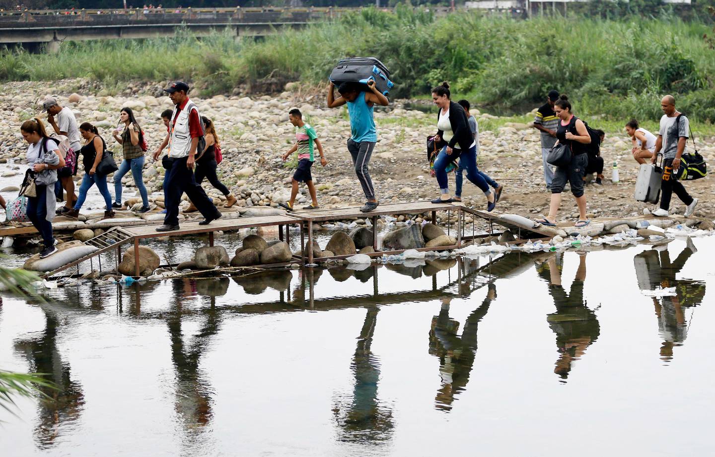 Bildet viser flyktninger som krysser ei elv i Venezuela.