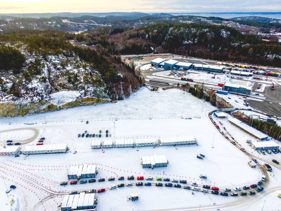 Bildet er av lange køer med biler på teststasjonen på Svinesund i desember. Det er snø på bakken, og bildet er tatt fra høyt oppe i lufta. Det står brakker rundt omkring på et stort område, hvor bilister kjører inn for å teste seg. Foto: Stian Lysberg Solum / NTB