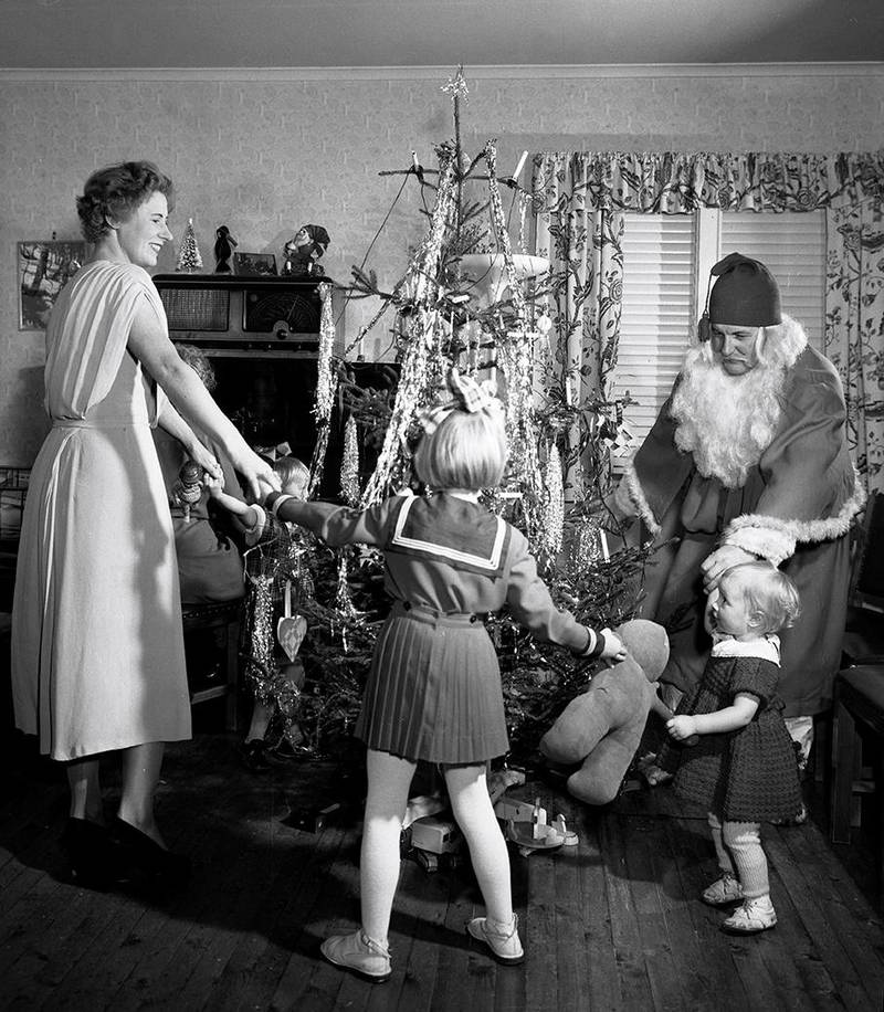 JULETRE: Ikke bare går vi mindre rundt juletreet hjemme. Vi synger også færre julesanger selv. Bildet er et gammelt bilde av folk som går rundt et juletre i et hjem. Ikke bare går vi mindre rundt juletreet hjemme. Vi synger også færre julesanger selv.