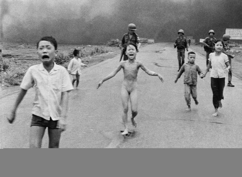 Bildet viser det berømte bildet av Nick Ut. Barn løper skrikende nedover gata. I midten er en naken Kim Phuc.