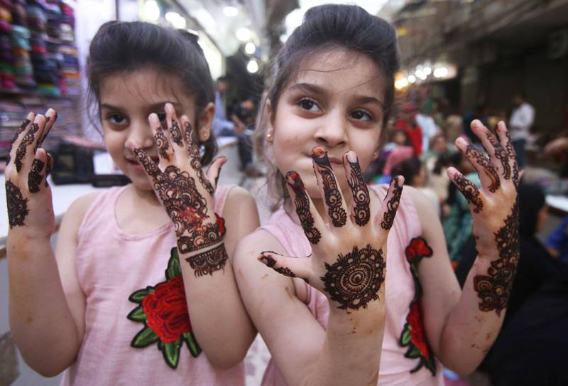 Bildet viser to jenter som har fått malt hendene med hennamaling.
