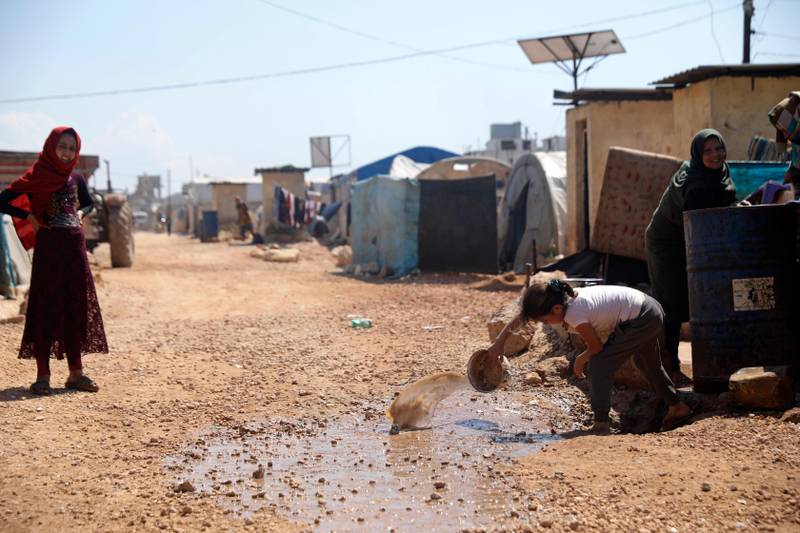 Bildet viser teltene i en flyktningleir utenfor byen Atma. Det er i Idlib i Syria. En person heller ut skittent vann.