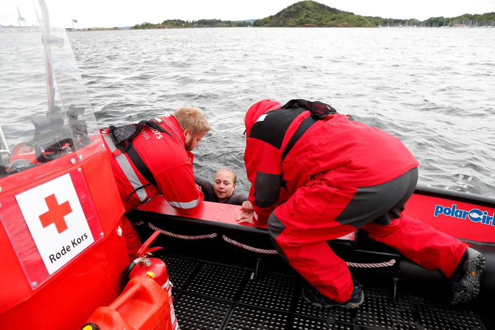 Bildet viser frivillige fra Røde Kors som øver på redning fra sjøen. To personer i båten hjelper en tredje opp fra vannet.