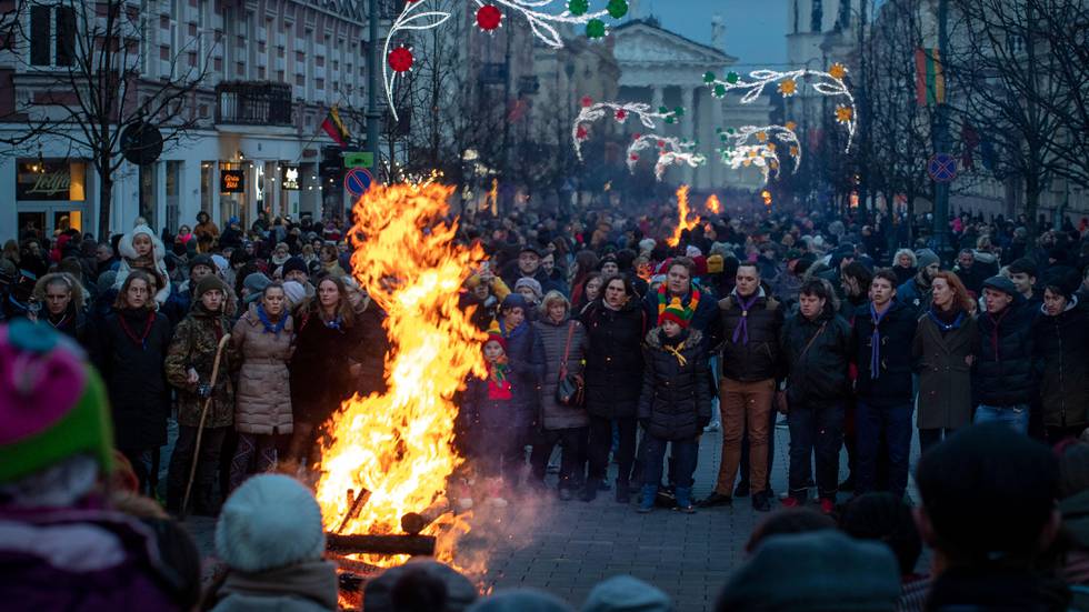 Bildet viser folk i Litauen som står rundt et bål.