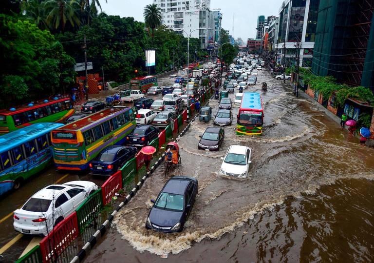 Dhaka i Bangladesh er en av de mest utsatte byene. Den ligger lavt og synker 1.4 centimeter hvert år. Her kommer sjåførene seg fram i vannet etter oversvømmelse under monsunen i juli.