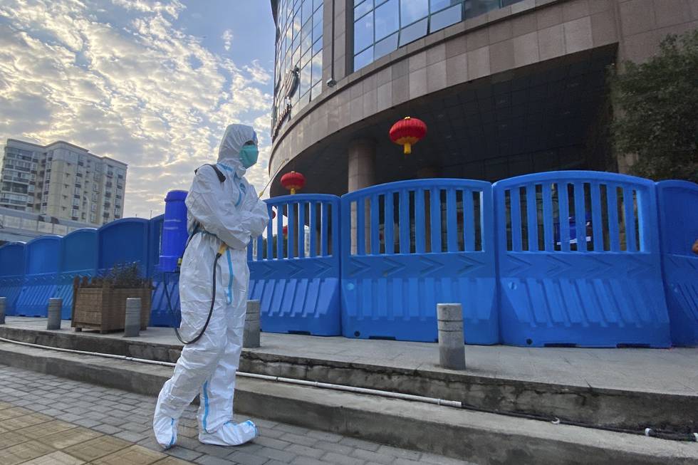 En arbeider i beskyttelsesutstyr utenfor sentralsykehuset i Wuhan 6. februar 2021. Hvordan viruset først ble spredt her, og senere i verden, er noe eksperter i Verdens helseorganisasjon (WHO) prøver å komme til bunns i. Foto: Ng Han Guan / AP / NTB