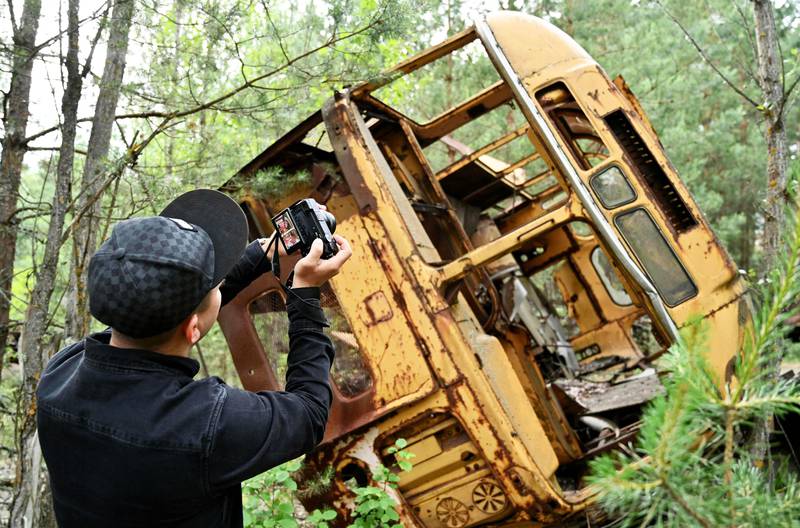 Bildet viser en turist som tar bilde av en havarert buss i byen Pripjat i Ukraina.