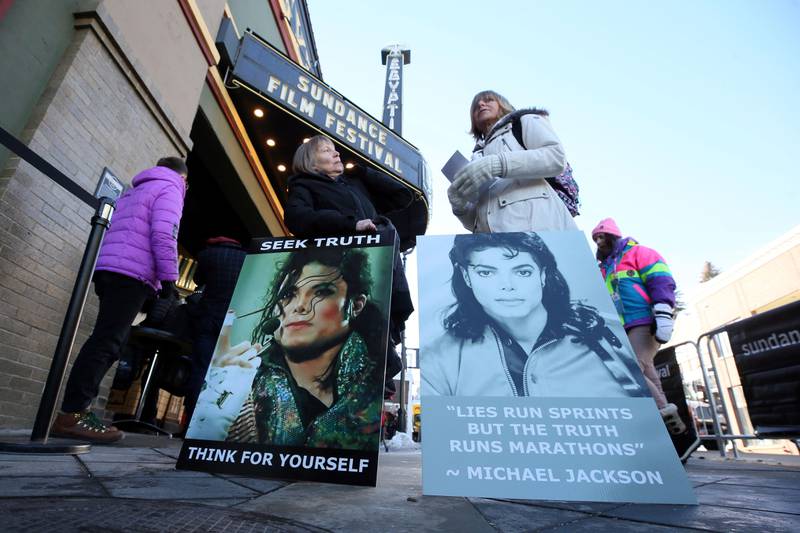 Bildet viser folk med plakater. De protesterte utenfor kinoer som viste dokumentaren om Jackson.