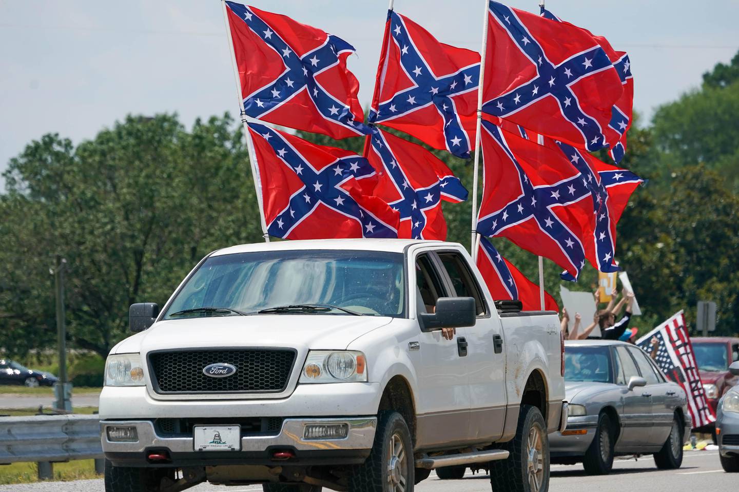 Bildet er av en pickup som har 9 synlige flagg på lasteplanet. Det er sørstats-flagg. De er røde, med et blått kryss som går fra hjørne til hjørne. I krysset er det hvite stjerner. Noen mener det er et flagg som handler om frihet. For andre er det et flagg som betyr undertrykkelse og rasisme.
