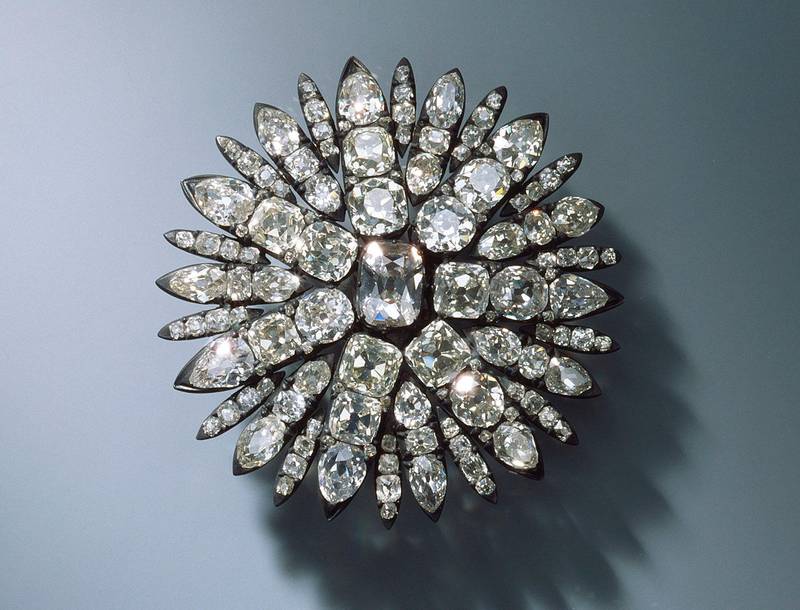 Bildet viser et smykke formet som en sol med diamanter.