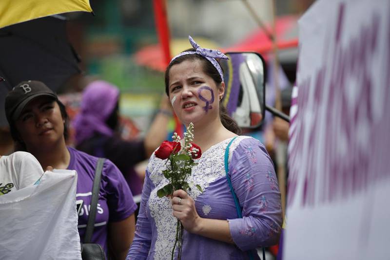 Bildet viser en kvinne som har malt seg i ansiktet og pyntet seg med lilla klær på Filippinene.