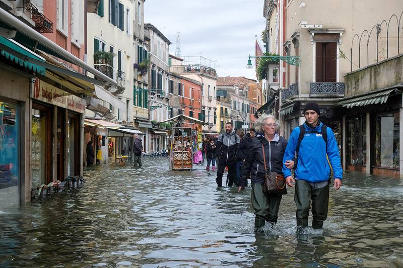Bildet viser folk som vasser i flomvannet i Venezia.