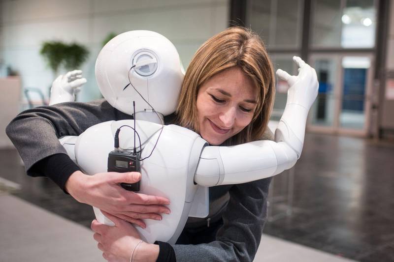 Bildet viser roboten Pepper som gir en dame en klem.