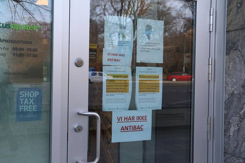Bildet viser plakater på døren til et apotek i Oslo sentrum. De er helt tom for håndsprit og munnbind. 
