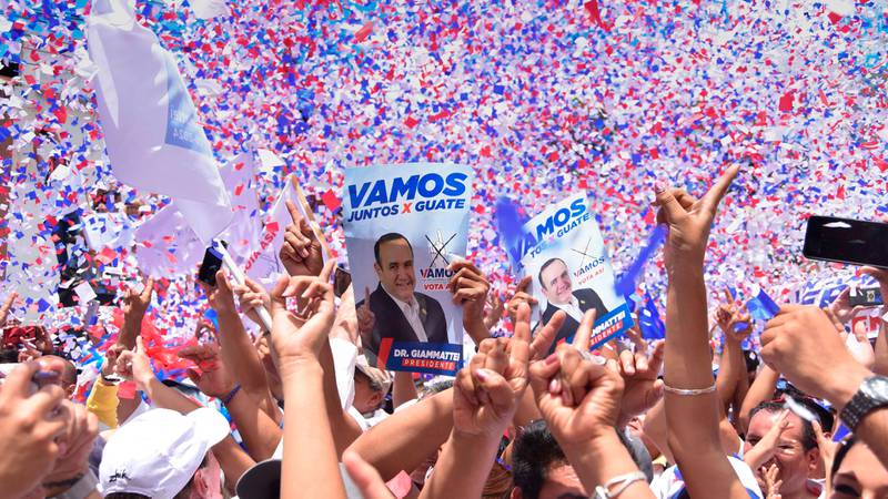 Bildet viser som folk jubler på et valgmøte for Alejandro Giammattei. Noen holder et bilde av ham med teksten «Vamos» over.