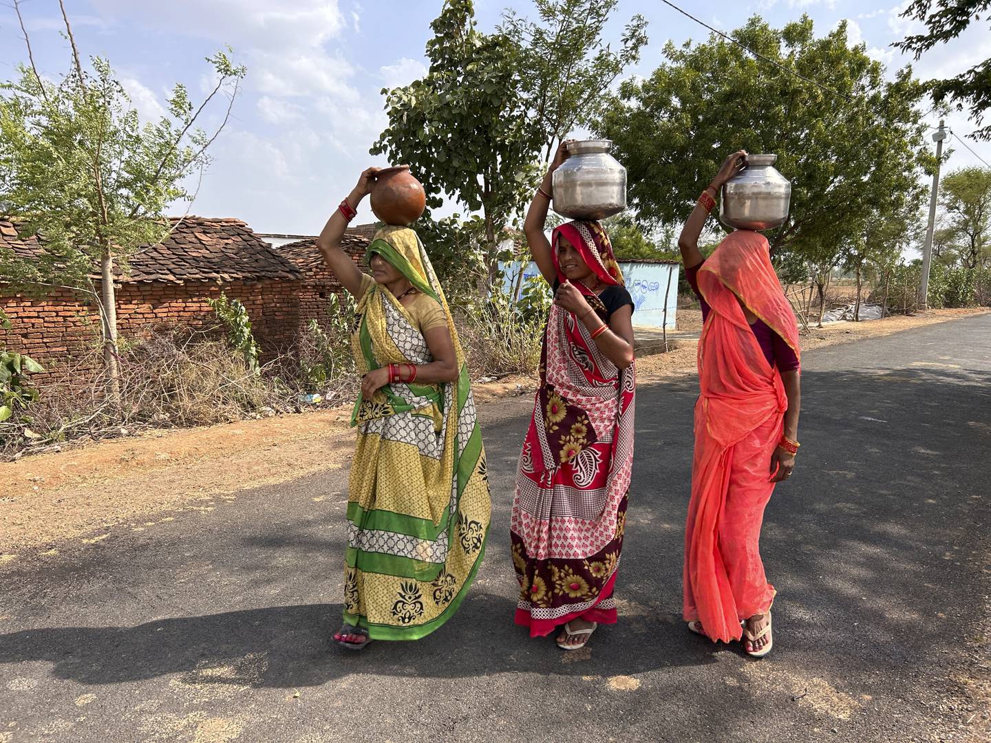 Tre kvinner går med krukker på hodet. De har fylt dem med vann for å hente til familien sin.