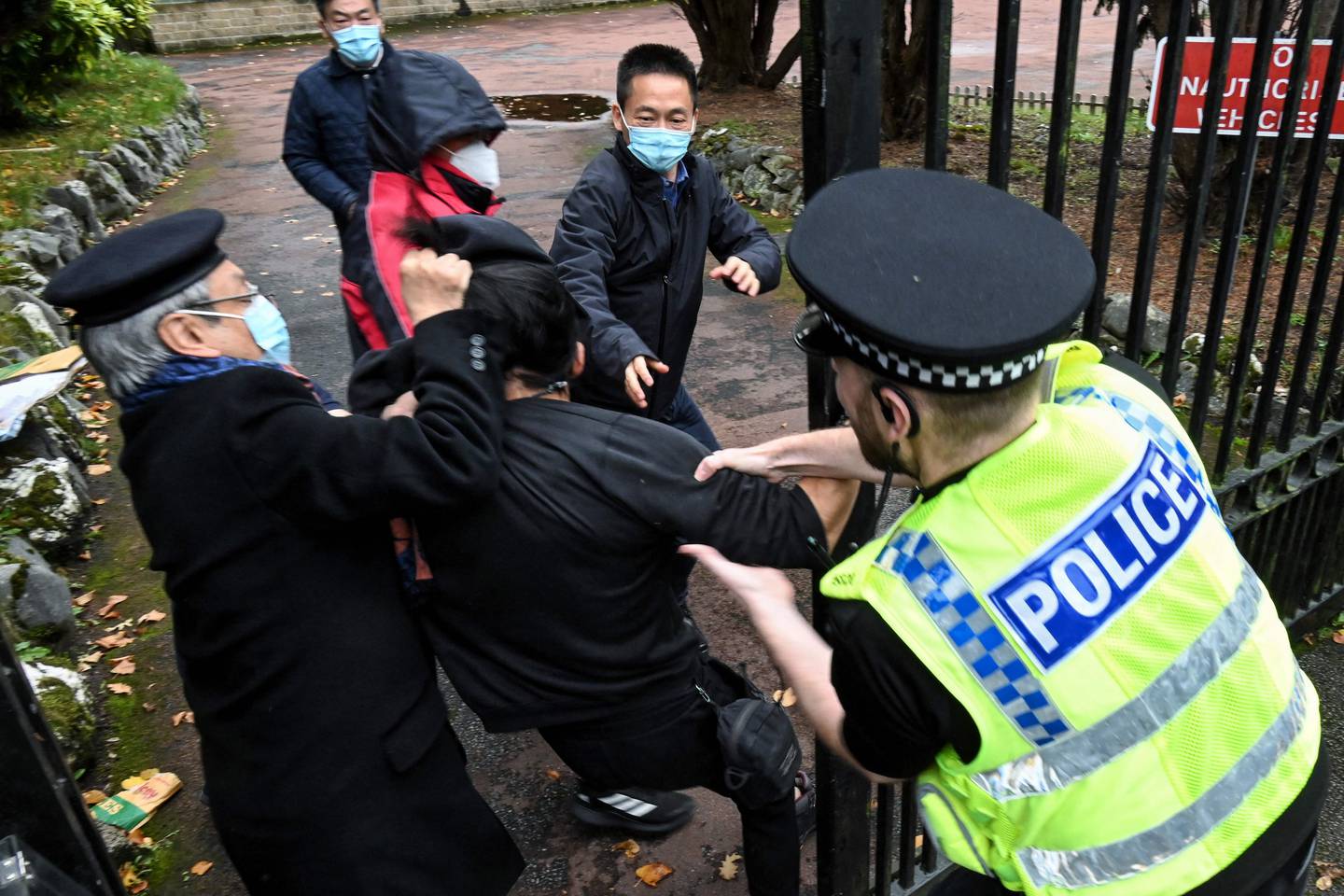 Bildet er av en mann som blir dratt i to ulike retninger av politi og ansatte ved Kinas konsulat i Manchester i England. Foto: Matthew Leung / The Chaser News / AFP / NTB
