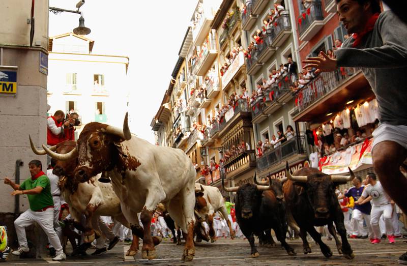 Bildet viser mennesker og okser i gatene i Pamplona i Spania.