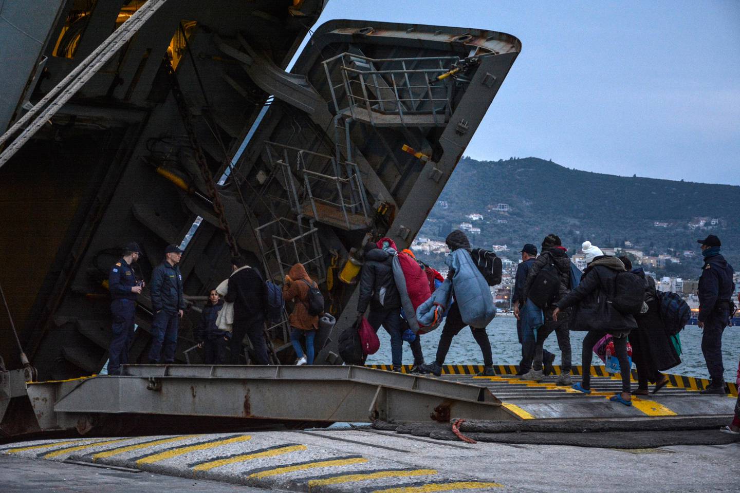 Migrants enter a Greek Navy ship which will accommodate them at the port of Mytilene on the northeastern Aegean island of Lesbos, Greece, on Wednesday, March 4, 2020. Turkey made good on a threat to open its borders and send migrants into Europe last week. In the past few days hundreds of people have headed to Greek islands from the nearby Turkish coast in dinghies. (AP Photo/Panagiotis Balaskas)