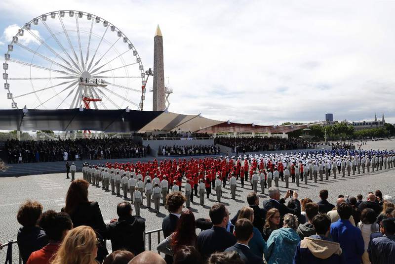 Bildet viser folk som står og ser på deler av militærparaden i Paris under landets nasjonaldag.