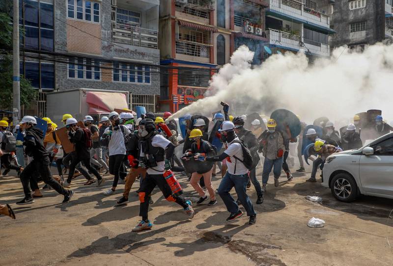 Bildet er fra protester i Myanmar. Folk løper fra opprørspoliti. Det blir brukt et brannsluknings-apparat for å få bort tåregass. Det fører til en stor røyksky.
