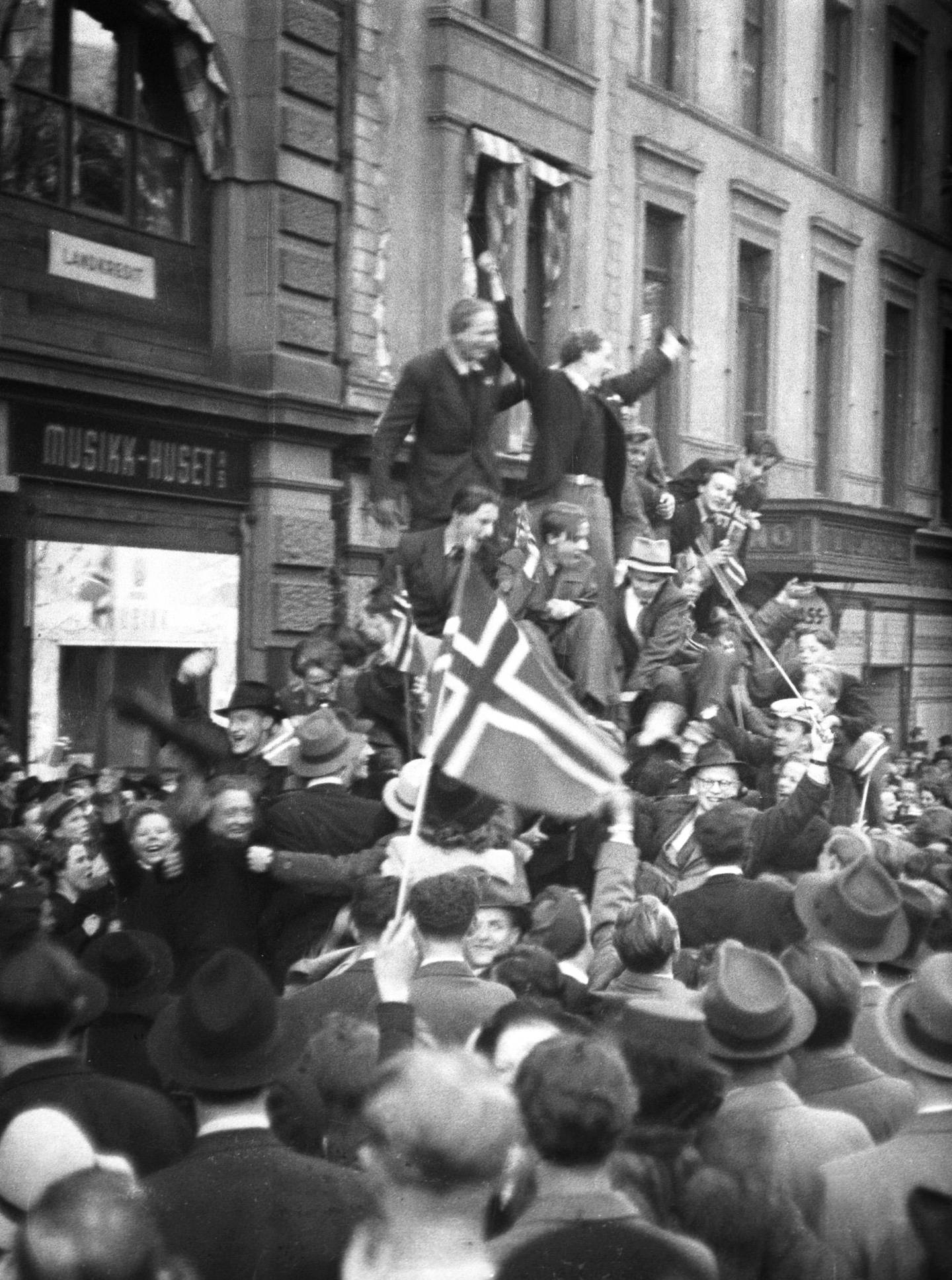 Oslo 19450508:  Fredsdagene mai 1945. Frigjøringsdagen 8. mai, jubel på Karl Johans gate. Biler fulle av jublende mennesker med norske flagg, folkemengder i gatene.
Foto: Kihle / NTB / Scanpix