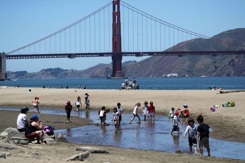 Bildet viser folk som plasker i vannet ved en strandlinje i San Fransisco i USA.