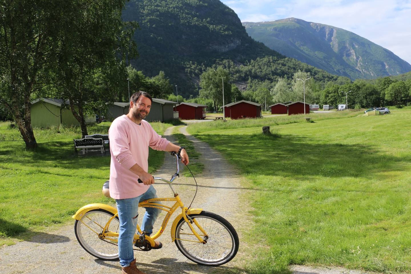 Bildet viser Kristoffer Nystedt på sykkel foran campinghyttene sine.